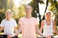 Group of young women practicing yoga, morning meditation in nature at the park