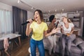 Young women spend free time in karaoke sing and have fun together with friends at home