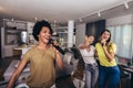 Young women spend free time in karaoke sing and have fun together with friends at home