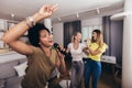 Young women spend free time in karaoke sing and have fun together with friends at home