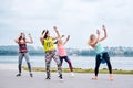 A group of young women, wearing colorful sports outfits, doing zumba exercises outside by city lake. Dancing training to loose Royalty Free Stock Photo
