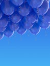 Grouped blue helium balloons with ribbons on blue sky