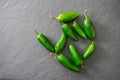 A grouping of bright green jalapeno peppers scattered on a gray cutting board with copy space Royalty Free Stock Photo