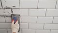 Workers' hands using a rubber spatula and grouting with paste between white ceramic tiles. Close-up of grout Royalty Free Stock Photo