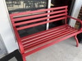 A iron red park bench on a sidewalk Royalty Free Stock Photo
