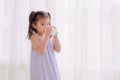 A growing Asian girl stands in her bedroom and enjoys a delicious breakfast of fresh milk