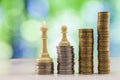 Growing coins stacks with green and blue sparkling bokeh background. Chess figures standing on coins meaning power and career Royalty Free Stock Photo