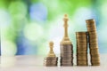 Growing coins stacks with green and blue sparkling bokeh background. Chess figures standing on coins meaning power and career Royalty Free Stock Photo