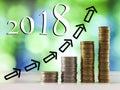 Growing coins stacks with green and blue sparkling bokeh background and 2018 chart arrows Royalty Free Stock Photo