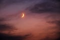 Growing moon in dramatic night sky among clouds. Warm colors of summer night Royalty Free Stock Photo