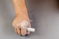 A grown man`s hand holds a piece of white chalk Royalty Free Stock Photo