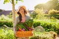 Grown by Mother Nature herself. Portrait of a young woman carrying a basket of freshly picked produce in a garden.