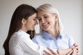 Grown up daughter enjoy moment of tenderness cuddling aged mother