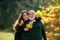 Grown up granddaughter with elderly grandfather hugs him talking standing outdoors. Caring adult daughter spend time