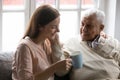 Grownup granddaughter visited old grandfather drinking tea enjoy meeting