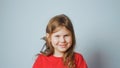 Grown up starling nestling sitting on shoulder of smiling little girl. Portrait of happy child on gray. Spring songbird.