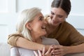 Grownup daughter hugging senior mom showing love and care