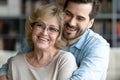 Grownup son hugs elderly mother laughing joking enjoy time together