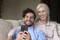 Grownup son relax with mother at home use smartphone Royalty Free Stock Photo