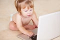 Growth, learning and a baby typing on a laptop on the floor of a living room in her home for child development. Kids