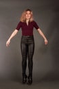 Growth Portrait of the blonde in the red sweater with short sleeves, leather trousers and boots. Studio shot on dark Royalty Free Stock Photo