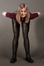 Growth Portrait of the blonde in the red sweater with short sleeves, leather trousers and boots. Studio shot on dark gray Royalty Free Stock Photo