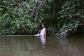 Growth portrait of a girl in a white dress standing in river