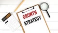 GROWTH STRATEGY words on clipboard, with calculator, magnifier and pencil on the white wooden background Royalty Free Stock Photo