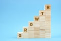 Growth word on wooden blocks staircase on blue background