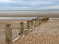 Groynes on Winchelsea Beach to stop the erosion by the tides and weather. Pebble beach with sea and sky landscape - East Sussex UK