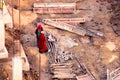 Ladies in saree and men in protective orange vests looking at metal pipes for the plumbing in the foundation of a real