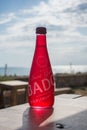 red plastic bottle of Badoit carbonated water on wooden table in front of the beach background Royalty Free Stock Photo