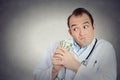 Grumpy greedy miserly health care professional holding money