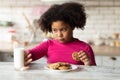 Grumpy Little Black Girl Refusing Milk And Eating Cookies In Kitchen