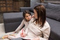 grumpy little daughter looking at mother with pencil and papers in hands