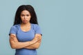 Grumpy woman. Portrait of serious black lady standing with crossed arms, posing over blue background with free space