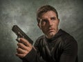 Grunge cinematic portrait of attractive and dangerous looking hitman or secret service especial agent man in action pointing gun