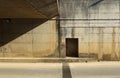 Grunge concrete block wall of a road underpass divided by shadow . Sidewalk and asphalt road in front. Royalty Free Stock Photo