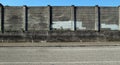 Grunge concrete wall with erased graffiti in the suburbs. A sidewalk and an asphalt road ahead. Royalty Free Stock Photo