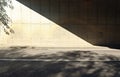 Grunge concrete wall of an underpass divided in two by the shadow of the bridge. Sidewalk and two lane road in front. Royalty Free Stock Photo