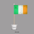 Grunge flag of Ireland on a stick, in a small bucket. Isolated on a gray background. Signs and symbols. Flags.Design