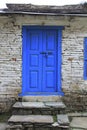 Grunge gray bricks wall with blue door of Nepali house.