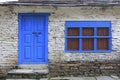 Grunge gray bricks wall with blue door and window of Nepal house