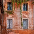 A grunge house orange wall and four windows in Trastevere historic neighborhood.