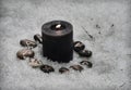 Grunge still life of black candle and runes in snow outside in winter