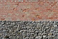 Grunge wall divided into two parts. In the lower part gray natural stones and in the upper part exposed bricks and concrete