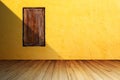 Grunge wood window on bright orange concrete wall against perspective wood floor with shadow from left side. Royalty Free Stock Photo