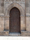 Grunge wooden ornate aged vaulted arched door on exterior decorated stone bricks