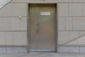 Grungy modern metal bronze door with copyspace into building with gray tiled concrete walls Royalty Free Stock Photo