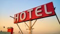 Grungy old hotel sign on a blue sky background with red background. White HOTEL logo closeup